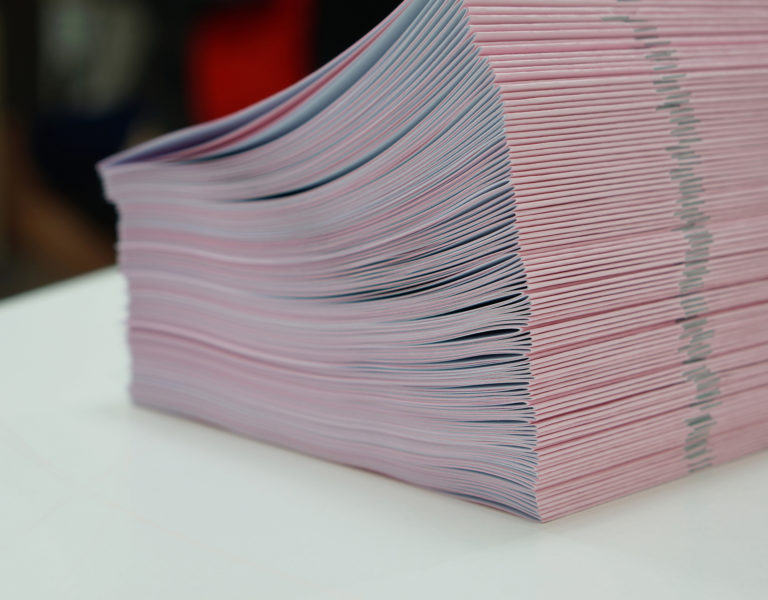 Piles of pink handout papers placed on table at office.