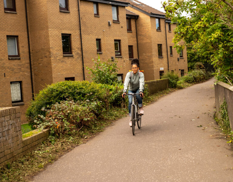 A woman cycling through a Scottish town.