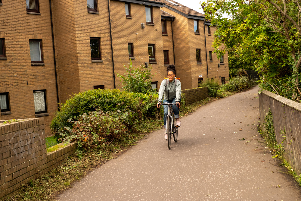 A woman cycling through a Scottish town.