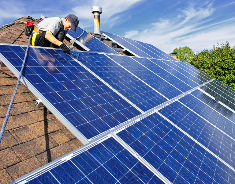 A stock photo of a man installing rooftop solar renewables. Community Wealth Building. Climate. Net Zero