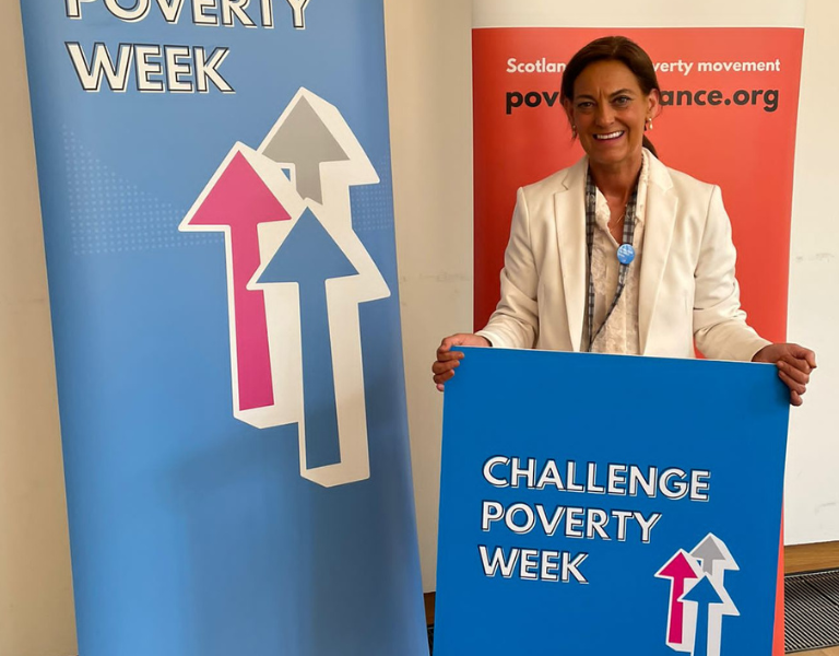 Collette Stevenson MSP holding a Challenge Poverty Week sign.