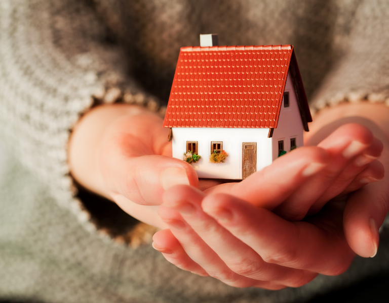 A stock image showing a woman holding a model house
