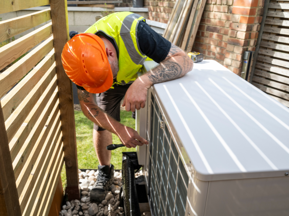 A stock image showing a workman installing an air source heat pump, to represent climate change and justice and a just transition.