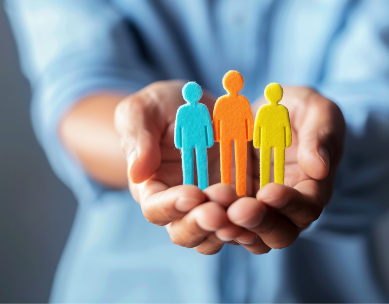 A stock image showing two hands cradling a cardboard cutout family.