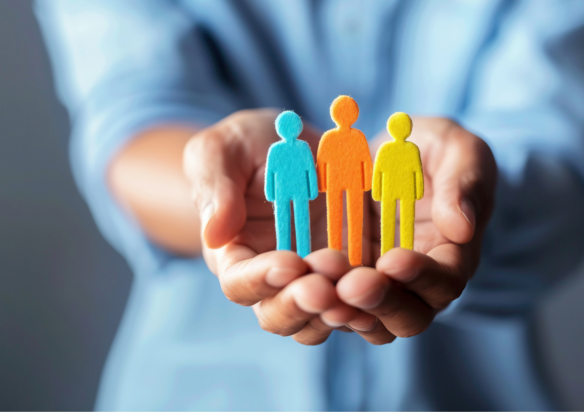 A stock image showing two hands cradling a cardboard cutout family.
