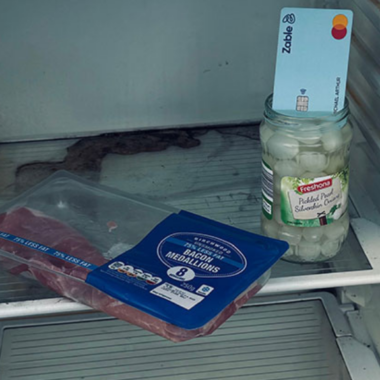 A photograph of an open fridge with very little on the shelves. Part of the Give Me Some Credit photovoice exhibition, taken by creator Michael John Arthur